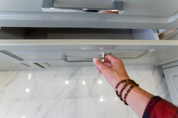 A person is in the process of opening a drawer located in a kitchen
