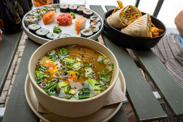 eating ramen soup in a restaurant with other food on the table in the background