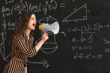Female Math teacher shouting into megaphone near blackboard in classroom
