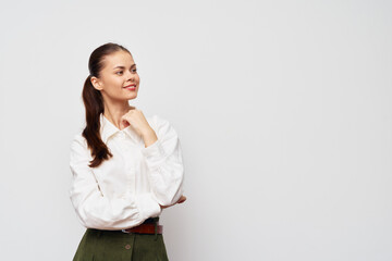 smiling woman in white shirt on plain background, looking to the side, thoughtful expression, casual attire, professional look, standing with arms crossed, confidence in her pose