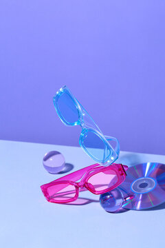Colorful Sunglasses and Floating CDs on a Purple Background