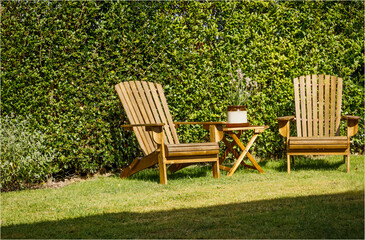 Two wooden chairs and a table in a garden