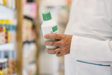 Pharmacist examining a bottle in a pharmacy aisle