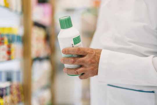 Pharmacist examining a bottle in a pharmacy aisle