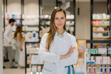 Confident pharmacist smiling with arms crossed in pharmaceutical store