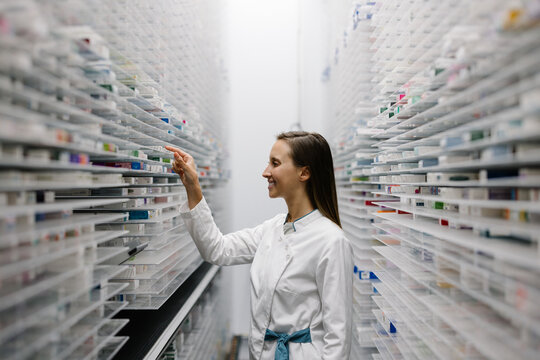 Pharmacist organizing medication in pharmacy storage area