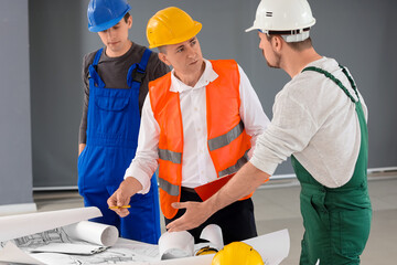 Team of male builders working in room