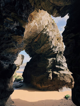View of sea and beach through gaps in a sea cave