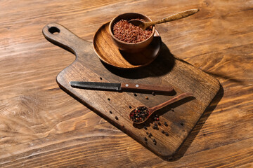 New cutting board and bowl with brown rice on wooden background