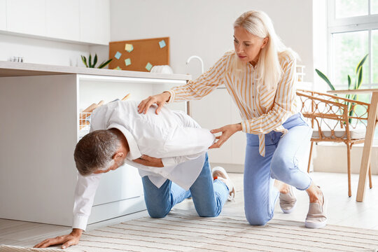 Mature woman and her husband having heart attack in kitchen - Powered by Adobe