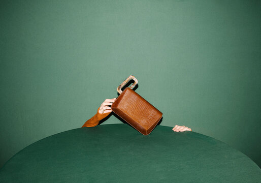 Abstract Image of Hands Holding a VIntage Brown Suitcase