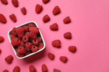 Bowl with fresh raspberries on pink background