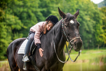 Child girl rides horse on the outdoors in the middle of the forest, park, trees, mountains. Girl on...