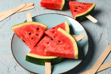 Plate with sweet watermelon sticks on blue background