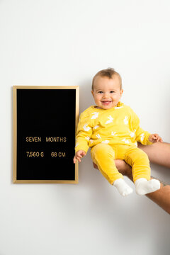 Seven months old baby in her father's hand next to development chart