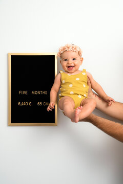 Five months old baby in her father's hand next to development chart