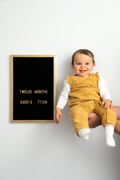 One year old baby in her father's hand next to development chart