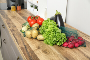 Eco bags with different fresh vegetables on counter in kitchen, closeup