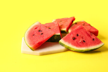 Board with pieces of fresh watermelon on yellow background