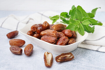 Bowl with dried dates on light background