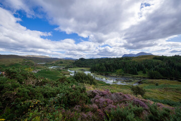 The image shows a body of water surrounded by hills in Loch a' Chàirn Bhàin, Scotland. The scene includes clouds, nature, water, sky, mountains, and a highland landscape.