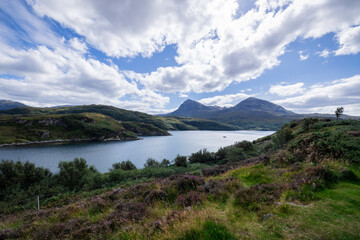 The image shows a body of water surrounded by hills in Loch a' Chàirn Bhàin, Scotland. The scene includes clouds, nature, water, sky, mountains, and a highland landscape.