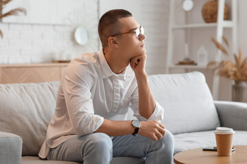 Young man with wristwatch sitting at home