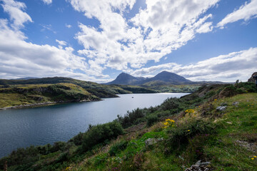The image shows a body of water surrounded by hills in Loch a' Chàirn Bhàin, Scotland. The scene includes clouds, nature, water, sky, mountains, and a highland landscape.
