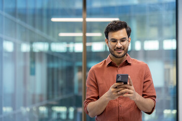 Young professional man in modern office using smartphone for communication and work