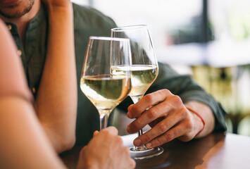 Couple toasting with white wine in a cozy restaurant setting