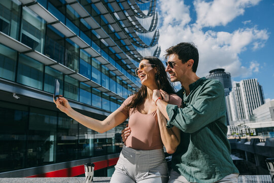 Couple taking a selfie on urban street in Madrid, enjoying sunny day