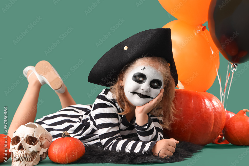 Wall mural Little girl dressed for Halloween with pumpkins and balloons on green background