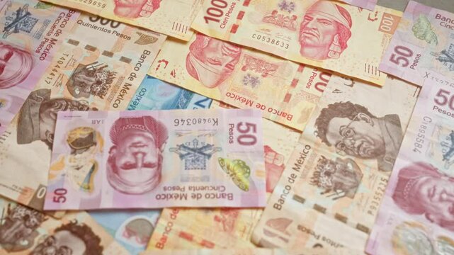 Mexican banknotes of various denominations from banco de mexico scattered in a pile, showcasing the diverse currency in mexico for financial and economic themes.