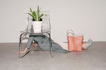 Woman Under Chair With Plant And Pink Purse On The Floor