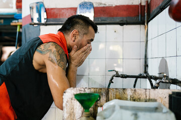 Mechanic Washing Hands in Garage
