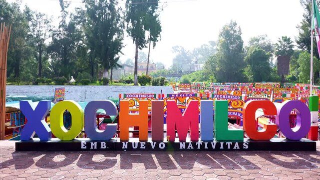 Letters with the name of Xochimilco with Colorful trajinera boats on the background in Xochimilco, area&rsquo;s pre-Hispanic past in the Valley of Mexico. Nativitas Pier.