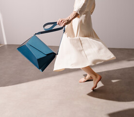 Graceful Woman in White Dress Holding Blue Leather Handbag