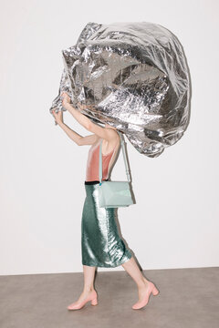 Fashionable Woman Carrying Large Metallic Sheet in Modern Outfit