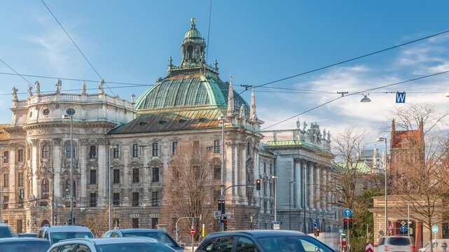 Exterior view of the Palace of Justice at the Karlsplatz timelapse in Munich, the capital of Bavaria, Germany. Traffic on the intersection with cars, buses and trams. Clouds on a blue sky
