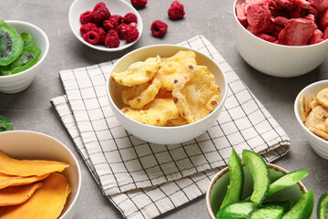 Bowls of different dehydrated fruits and berries on grey background