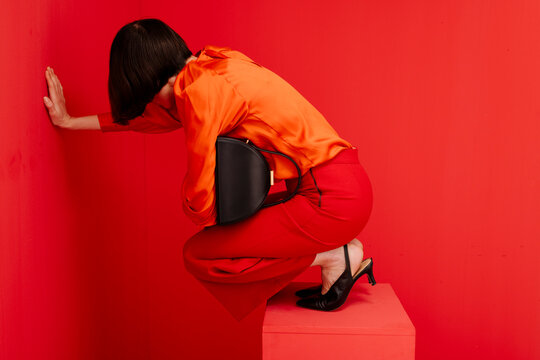 Woman Posing Against Red Background in Orange Outfit