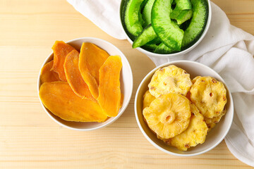 Bowls of different dehydrated fruits on wooden background