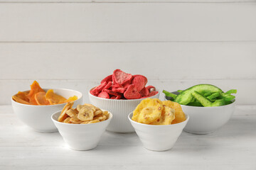 Bowls of different dehydrated fruits and berries on white wooden background