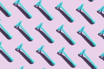 Pattern of blue razors with contrast shadows on a purple background. Personal care and grooming concept. Top view, copy space