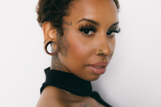 Close-up of a woman with piercings and tattoos, isolated on white