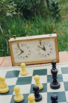 Still life of a analog clock with a chess board 