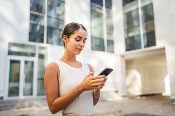 Young woman stand in front company building and use mobile phone