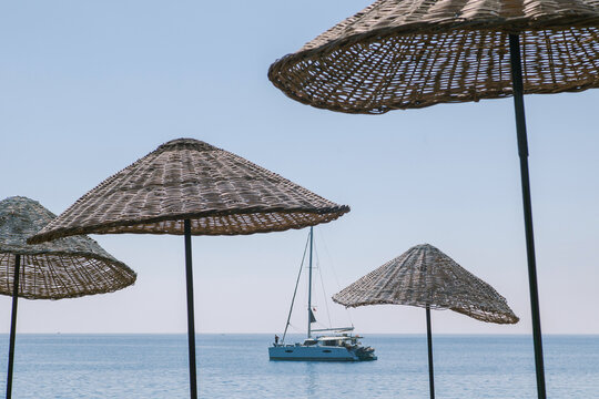 A yacht sails along the sun umbrellas on the beach