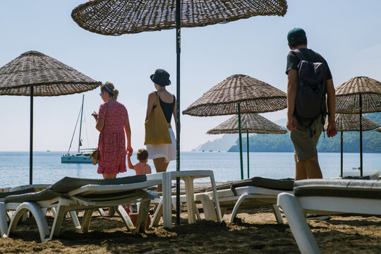 Friends looking for a free spot on the beach under sun umbrellas