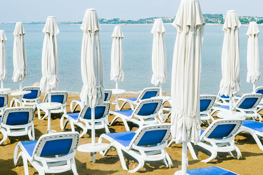 Empty sunbeds and closed sun umbrellas to the beach